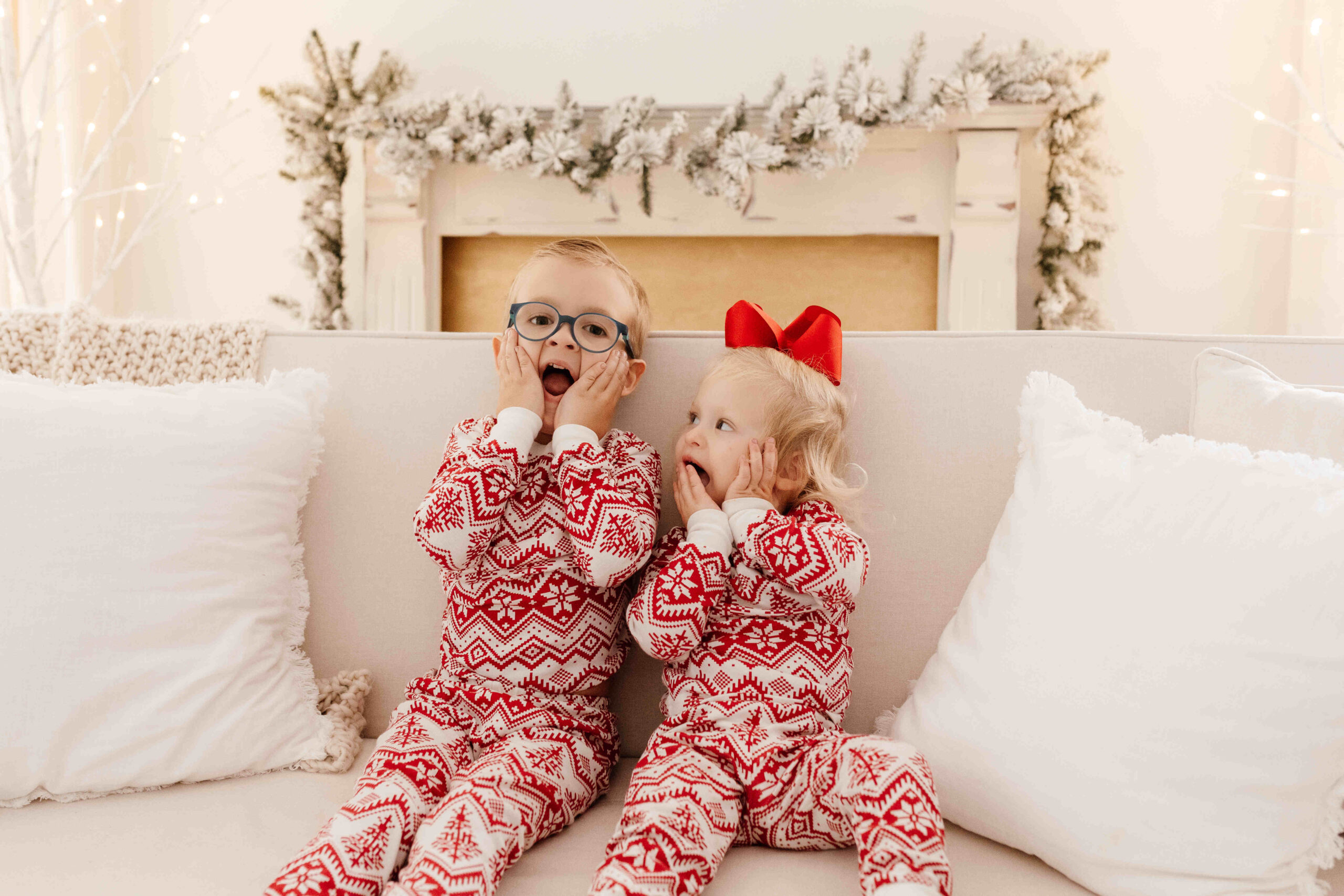 Young siblings in matching pajamas sitting on the holiday set looking at the camera making silly faces. JCrane Photography, Seasonal Sessions, Special Offers, holiday family photos Raleigh, Classic Family Photography, Limited Time Offer, Local Photography